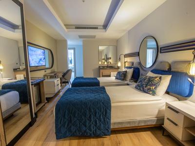 Modern hotel room with double bed, mirror, and bedside tables.