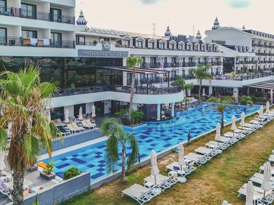 Large hotel pool with sun loungers and palm trees along the outdoor pool.