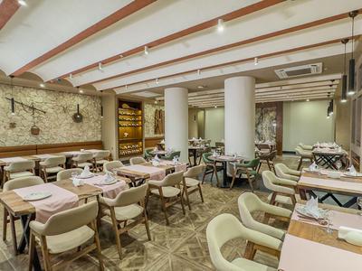 Nowoczesna restauracja hotelowa z nakrytymi stołami i wygodnymi krzesłami pod odsłoniętymi belkami sufitowymi.