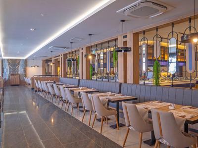 Modern hotel restaurant with long tables, stylish chairs, and decorative lighting.