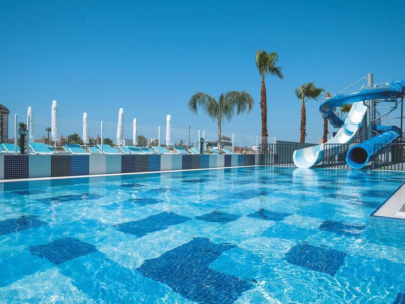 Pool bar with built-in stools, column, and sun umbrellas by the hotel pool.