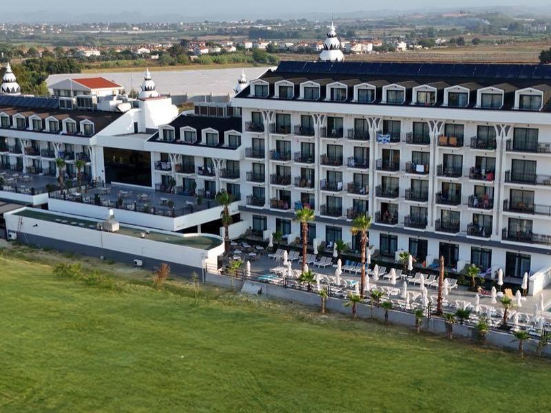 Large multi-story hotel building with pools, surrounded by green lawns.