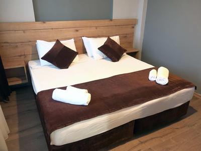 Modern tweepersoonsbed met bruin-wit beddengoed in een hotelkamer