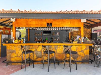 Open bar met geel stenen patroon en drie hoge krukken onder een dak.