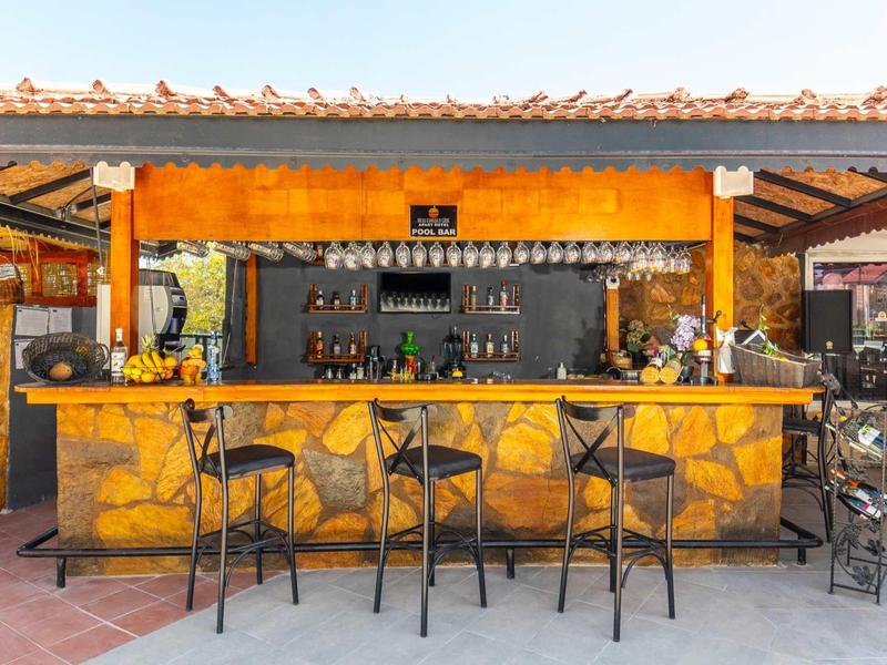 Open bar met geel stenen patroon en drie hoge krukken onder een dak.