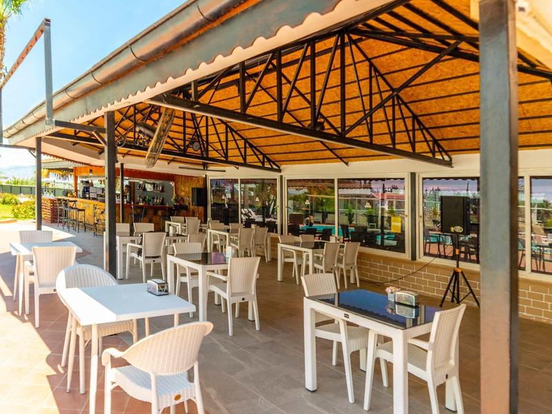 Overdekt buitenterras met tafels en stoelen bij een hotelrestaurant.