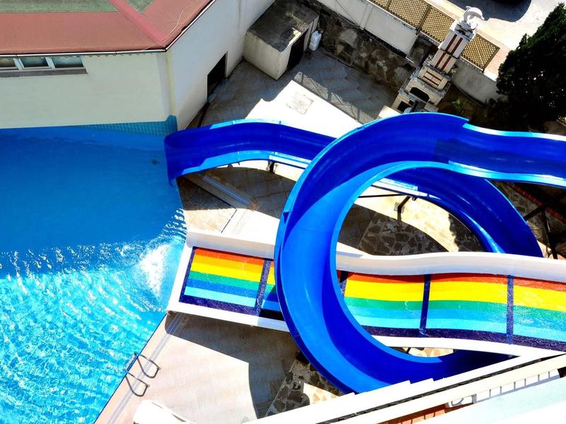 Zicht op blauwe glijbanen die in een zwembad in een hotelgebied uitkomen.