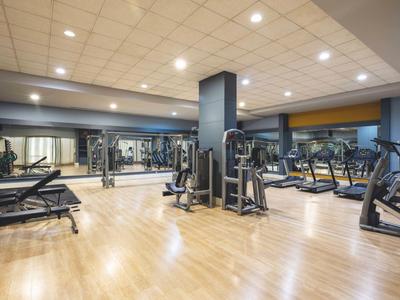 Moderne fitnessruimte met diverse trainingsapparatuur en houten vloer.