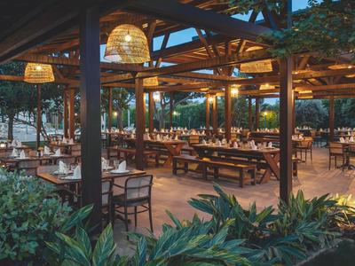 Venkovní restaurace s dřevěným nábytkem a osvětlením večer v hotelu.