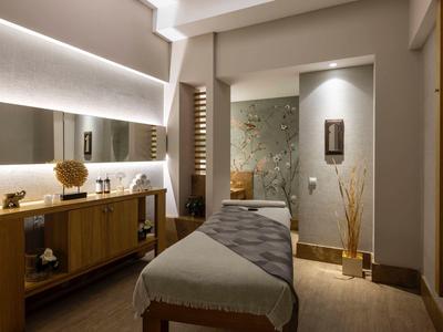 Příjemná spa místnost s masážním stolem, dřevěným nábytkem a tlumeným osvětlením.