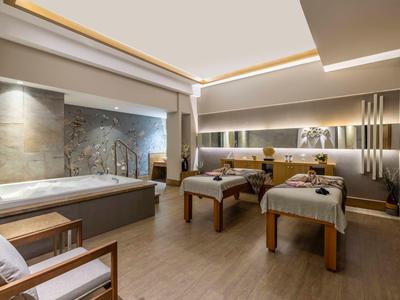 Moderní spa místnost se dvěma masážními stoly, velkou vanou a relaxační atmosférou.