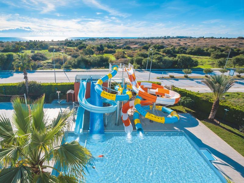 Barevné vodní skluzavky v bazénu s okolní krajinou a modrou oblohou