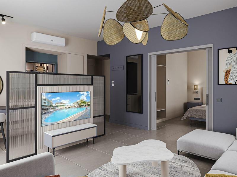 Moderní obývací prostor s pohovkou, TV a přístupem do ložnice v hotelovém pokoji.