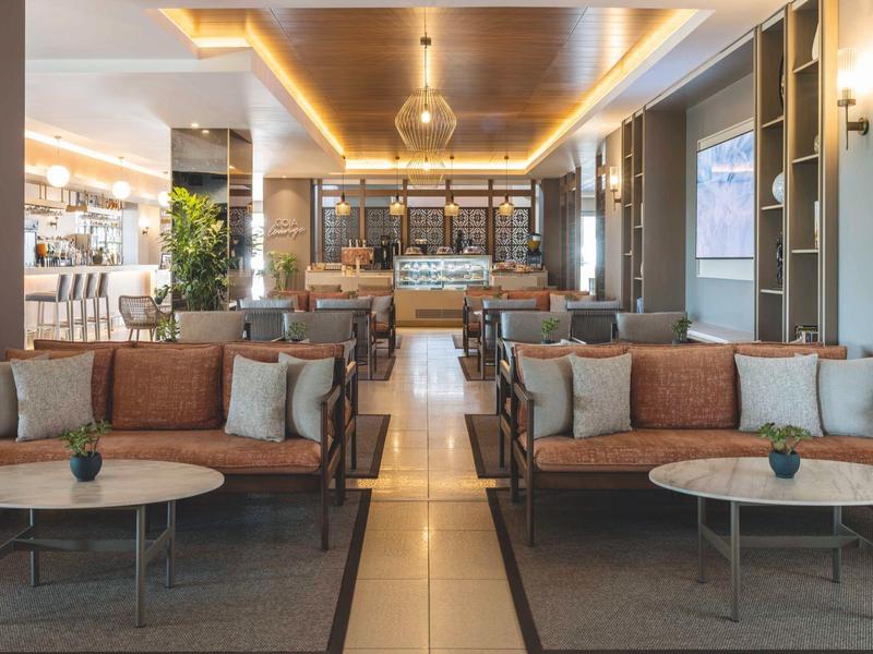 Moderně zařízená hotelová lobby s posezením, stolky a nepřímým osvětlením.