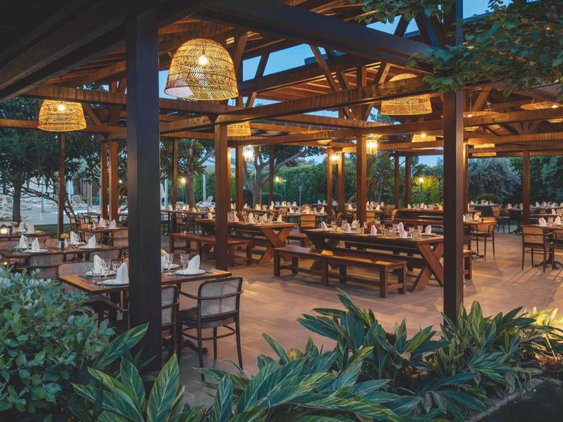 Venkovní restaurace s dřevěným nábytkem a osvětlením večer v hotelu.