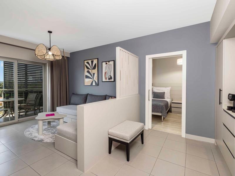 Moderně zařízený obývací pokoj s pohovkou, konferenčním stolkem a přístupem na balkon se sezením.