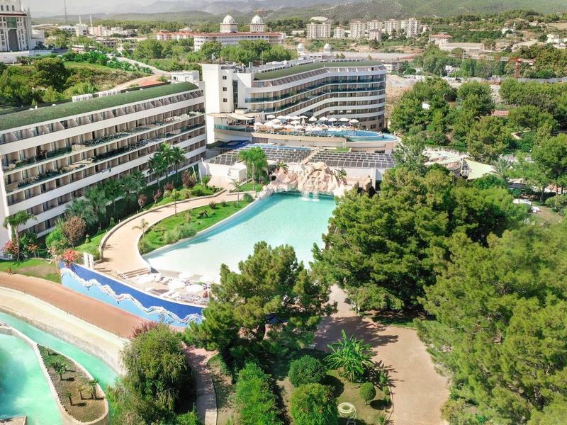 Hotel z wieloma basenami, zjeżdżalniami wodnymi i otoczony zielenią w mieście.