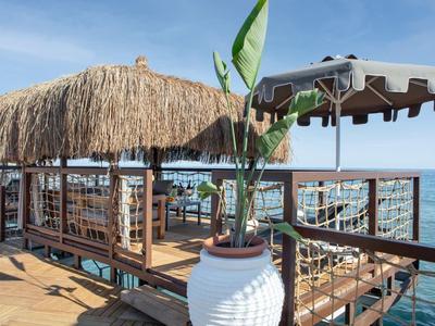 Lounge coperta con tetto di paglia e comodi posti a sedere sulla spiaggia con vista mare.