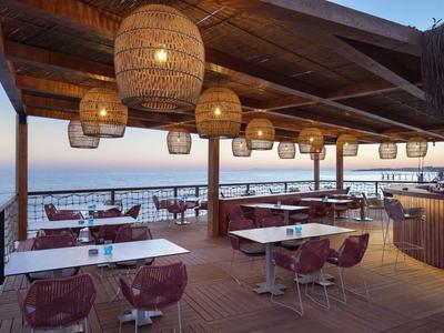 Ristorante aperto con tetto in legno e lanterne vicino al mare al tramonto.