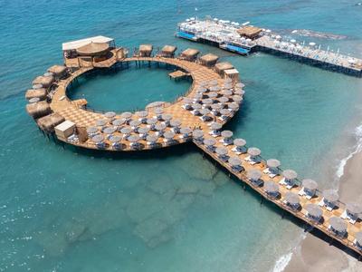 Resort circolare con bungalow sull'acqua e accesso alla spiaggia.