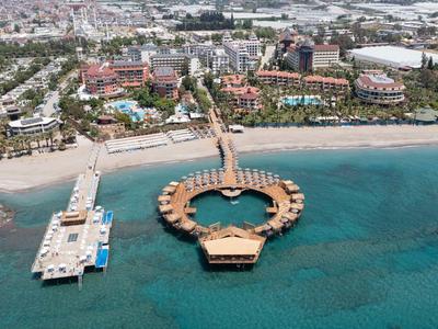 Resort di lusso con spiaggia, più piscine e un pontile a forma di cuore in acqua blu chiara.