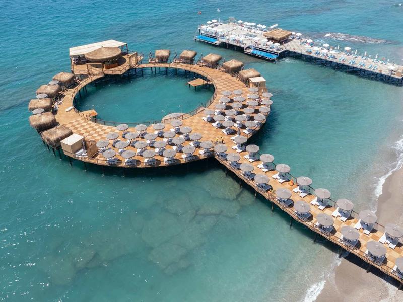 Resort circolare con bungalow sull'acqua e accesso alla spiaggia.