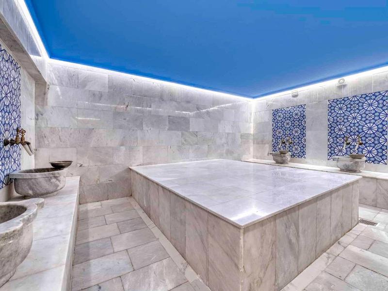 Hammam moderno con superfici in marmo e piastrelle decorative blu e bianche sulle pareti.