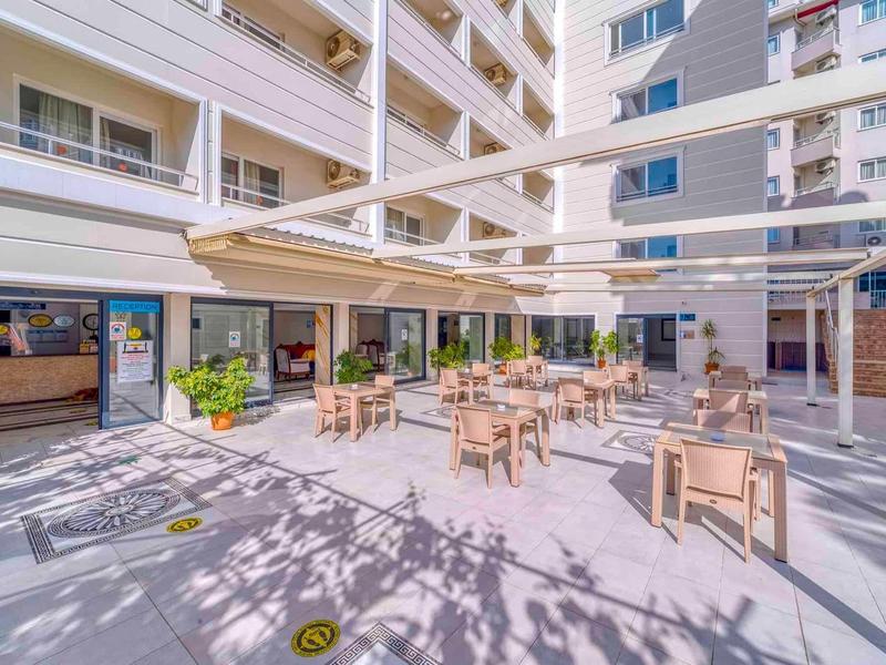 Area esterna di un hotel con tavoli, sedie e uno spazio coperto per rilassarsi.