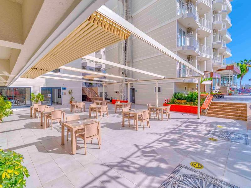 Ristorante all'aperto con tavoli e sedie sotto una tenda vicino a un edificio dell'hotel.