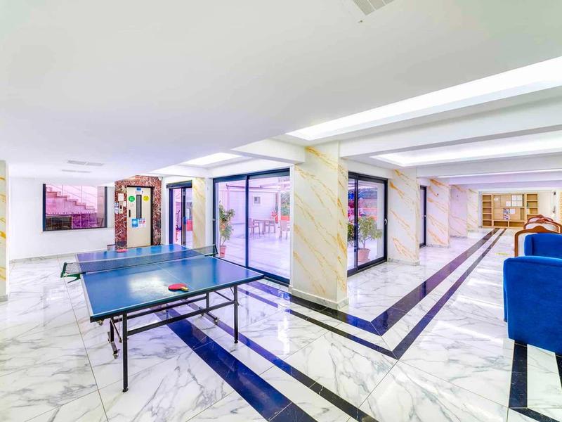 Area giochi moderna con tavolo da ping pong e zona salotto in un hotel luminoso.