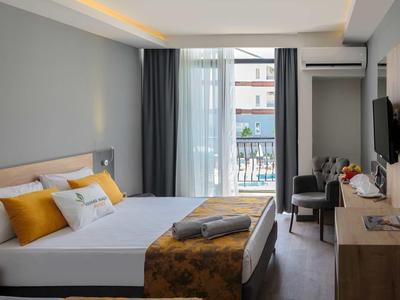 Nowoczesny pokój hotelowy z podwójnym łóżkiem, biurkiem, telewizorem i balkonem z widokiem na miasto.