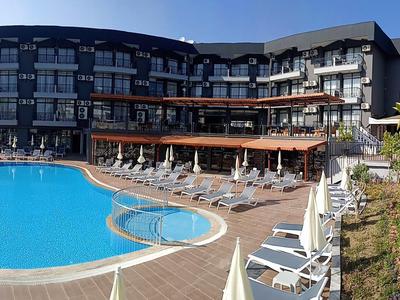 Complexe hôtelier moderne avec grande piscine extérieure et chaises longues par temps ensoleillé.