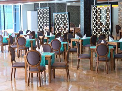 Nowoczesna jadalnia z krzesłami o okrągłych oparciach i stołami z zielonymi obrusami.