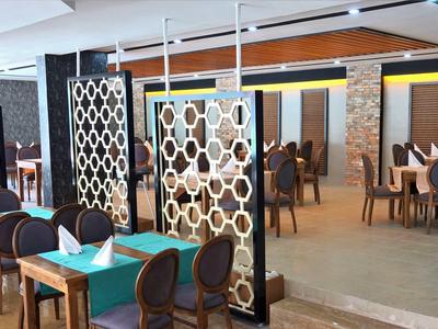 Moderner Gastraum mit Holztischen, blauen Tischdecken und dekorativen Raumteilern aus Holz und Glas.