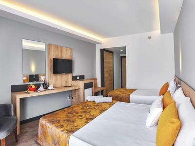 Nowocześnie urządzone pokoje hotelowe z dwoma łóżkami, telewizorem i przytulnym miejscem do siedzenia.