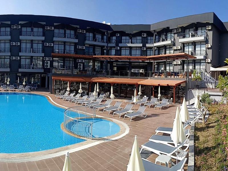 Nowoczesny kompleks hotelowy z dużym basenem na zewnątrz i leżakami pod czystym niebem.