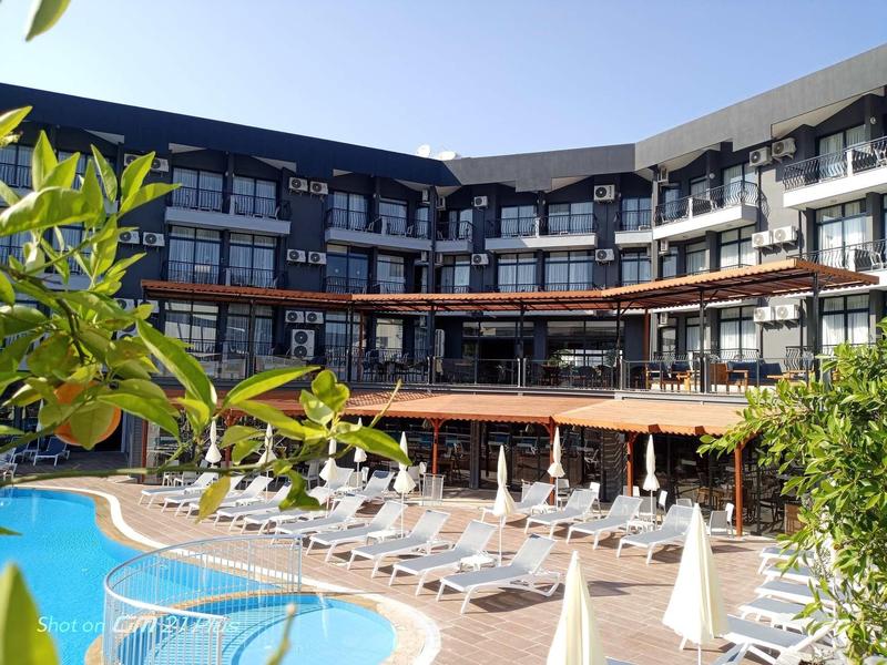 Hotel z dużym basenem, leżakami i parasolami na dziedzińcu.