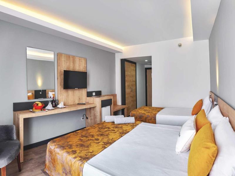 Nowocześnie urządzone pokoje hotelowe z dwoma łóżkami, telewizorem i przytulnym miejscem do siedzenia.