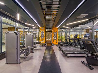 Moderner Fitnessraum mit Laufbändern, Gewichten und Spiegeln in hellem, geräumigem Raum.