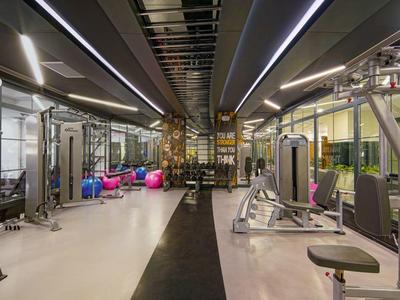 Modernes Fitnessstudio mit Fitnessgeräten, Hanteln und hellem, großzügigem Innenraum.