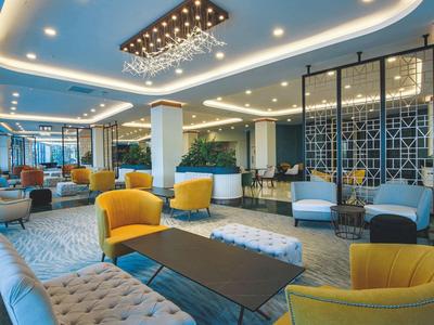 Helle Lobby mit bequemen Sesseln in Gelb und Blau, modernen Tischen und stilvollen Deckenleuchten.