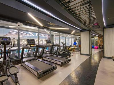 Salle de sport moderne de l'hôtel avec tapis de course et machines de musculation sous éclairage LED.