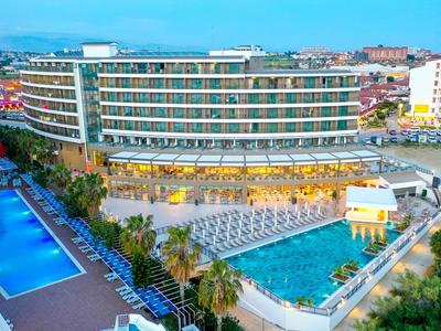 Hôtel moderne à plusieurs étages, avec deux grandes piscines extérieures et de nombreux transats.