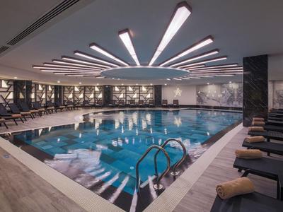 Piscine intérieure moderne avec éclairage indirect et chaises longues dans un spa d'hôtel.