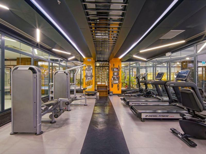 Moderne hotelgym met loopbanden en fitnessapparaten in een strak, goed verlicht ruimte.