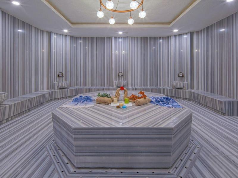 Luxe sparuimte met gestreepte muren, centrale marmeren tafel en zachte verlichting.