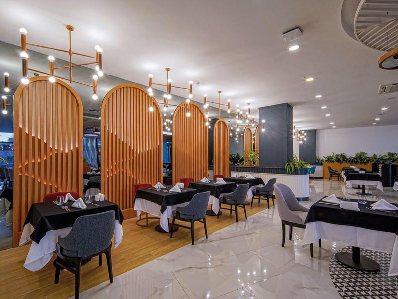 Moderne hotel eetruimte met elegante verlichting, zwarte tafelkleden en comfortabele zitplaatsen.