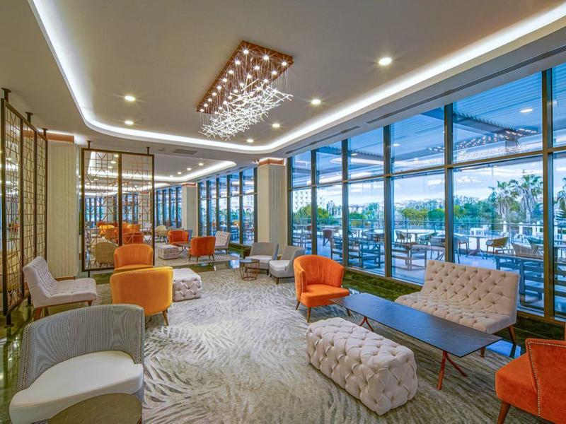 Moderne hotel lounge met ramen van vloer tot plafond en uitzicht op balkon en landschap.