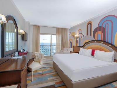 Stanza d'hotel con letto grande, scrivania, sedia e balcone con vista mare