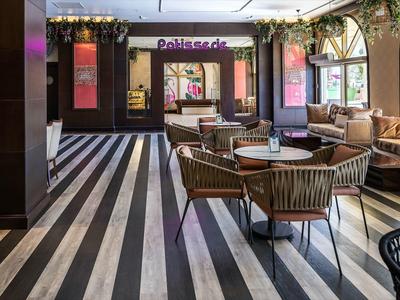 Moderní kavárna s pruhovanou podlahou a pohodlným sezením u velkých oken.